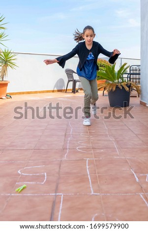 Beautiful little girl in a black jacket playing hoof with a clothespin on the terrace of her house. Fun concept