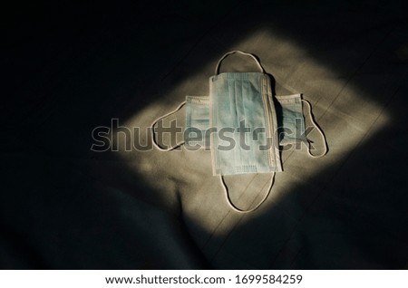 Two medical mask are stacked as a plus sign.two medical mask in dark room.
two mask on black background.medical mask  in the room is exposed to light.Prevent COVID-19.