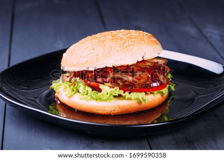 Fresh burger over wooden table and dark background. Front view