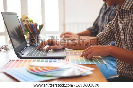 The designer works with a laptop while also designing colors for his work.