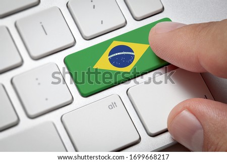 Online International Business concept: Computer key with the Brazil on it. Male hand pressing computer key with Brazil flag. Royalty-Free Stock Photo #1699668217