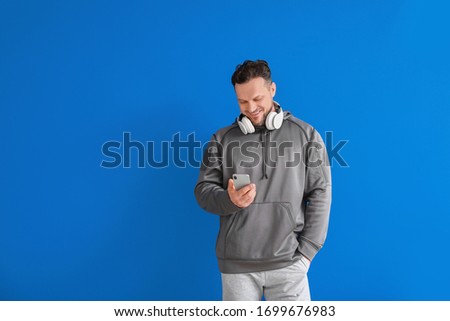 Stylish man with mobile phone on color background