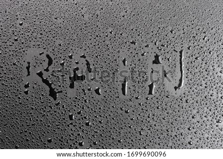 the word rain handwritten on matte black hydrophobic matte surface with water drops