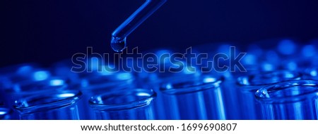 Test tube row. Concept of medical or science laboratory, liquid drop droplet with dropper in blue tone background, close up, micro photography picture.