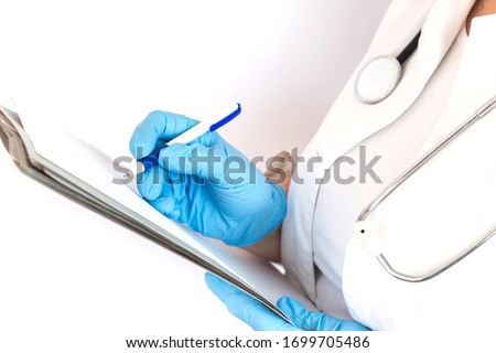 doctor in a white coat and medical blue gloves records a patient's medical history, close up