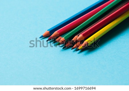 Set of colored pencils on blue paper for design.