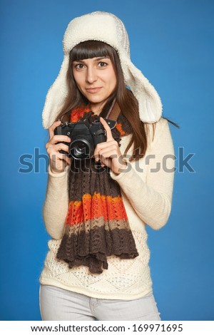 Woman photographer holding photo camera over blue background