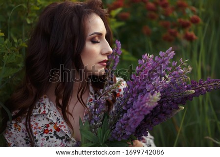 beautiful brunette holding lupine flowers, evening makeup.