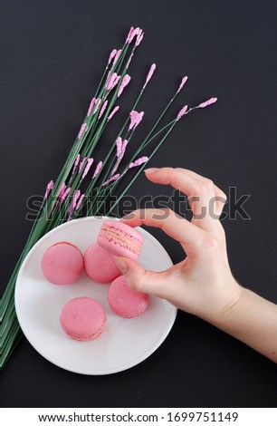 The hand holds a delicious macaroons, on a black background.
