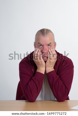 older retired mature man in studio, making funny silly comic faces. casual dress.