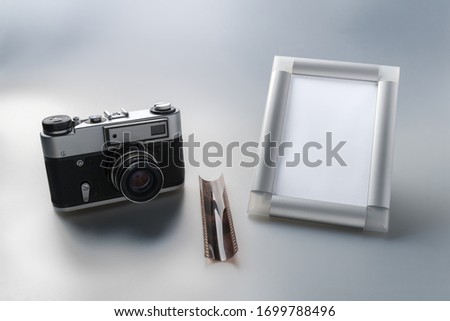 Vintage camera, film and stylish empty photo frame on a gray gradient background. Layout. Stylized stock photos.
