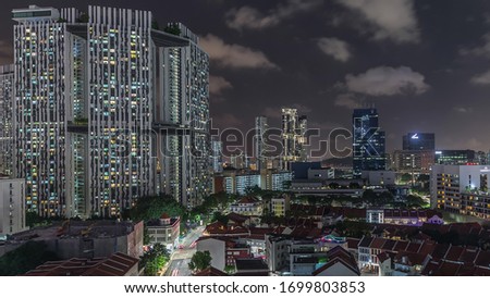 Aerial view of Chinatown with red roofs and Central Business District illuminated skyscrapers view, Singapore. Contrast between old and modern buildings. Traffic on streets