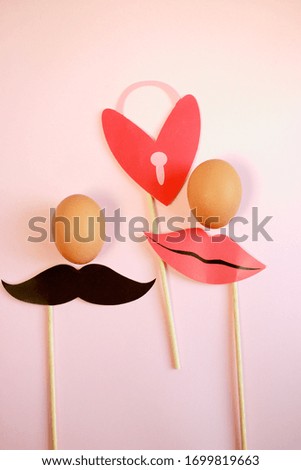 Eggs. Pale pink background. Pictures for a photo shoot, moustache and lips. Heart with a lock
