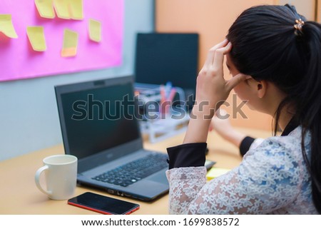 A woman sitting at work with a computer at home with stress, Unhappy person use computer technology at home, Upset woman looking at laptop screen. (out of focus, soft focus) Royalty-Free Stock Photo #1699838572