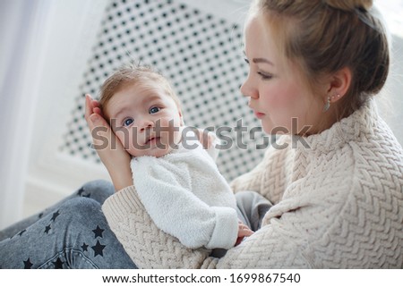 Young mother holding her newborn child. Mom nursing baby. Woman and new born boy relax. Nursery interior Family at home. Portrait of happy mother and baby