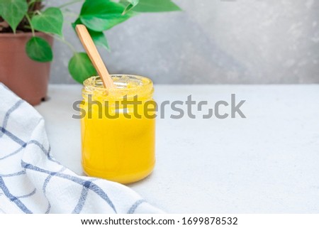 Ghee or clarified butter in a glass jar on a neutral textured background with copy space Royalty-Free Stock Photo #1699878532