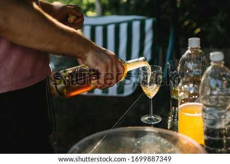 On a sunny day, a man pours wine in the boklah outdoors. Mans hand pouring wine into glass.