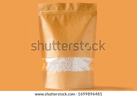 striped brown paper doy pack stand up biodegradable pouch with window zipper on brown background filled with rice