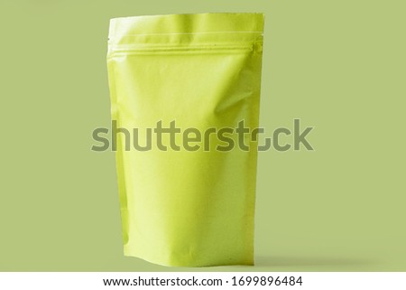 close up of matt green paper doypack stand up packaging pouch with zipper on light green background Royalty-Free Stock Photo #1699896484