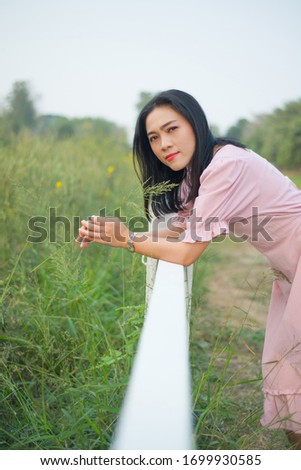 Asian woman take picture with white fence on field show travel background
