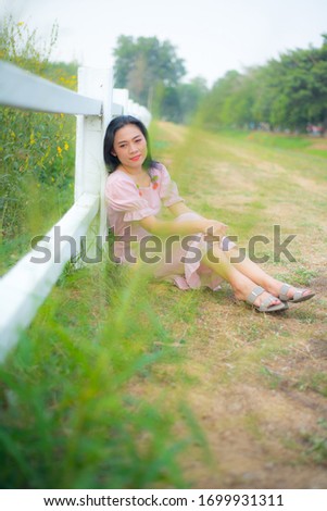 Asian woman take picture with white fence on field show travel background