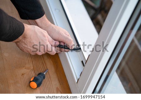 Professional master at repair and installation of windows, changes rubber seal gasket in pvc windows. Royalty-Free Stock Photo #1699947154