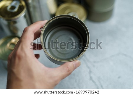 Man hand holding empty can with group of Aluminium canned food.