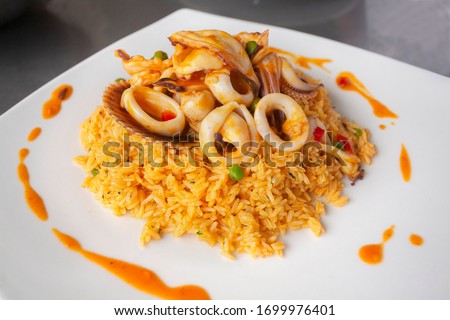 Peruvian food: arroz con mariscos or rice with seafood decorated with squid and clam, served on a white plate Royalty-Free Stock Photo #1699976401