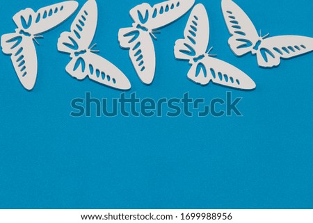 The concept of nature in spring. Minimal flatley composition, top view. White butterflies on a blue background, a creative minimal concept, copy space.