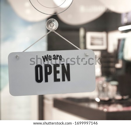 white plastic  sign board hanging on door of clothing store
