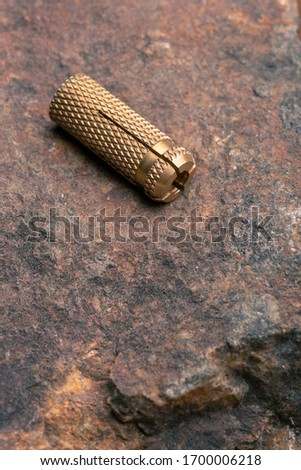 Brass drop anchor for concrete. Brass drop anchor lying on a rock.