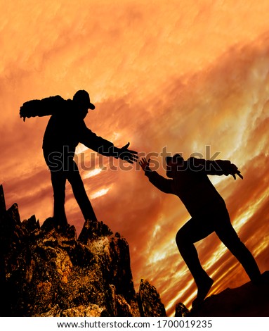Helping Hand. Take my Hand to Hearten you.Man giving hand a male to help her to climb the mountain. Help concept hand reaching out to help friend in orange sunset sky  background