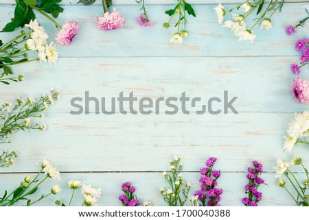 Flat lay of various colorful spring flowers frame with copy space on wooden background