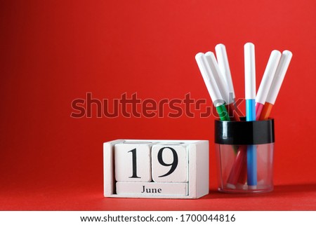 Wooden calendar with the date of June 19, felt-tip pens, on a red background