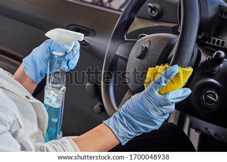 Woman in rubber protective glove disinfecting car steering wheel. Cleaning vehicle inside for protection from Coronavirus disease. Epidemic Outbreak Royalty-Free Stock Photo #1700048938