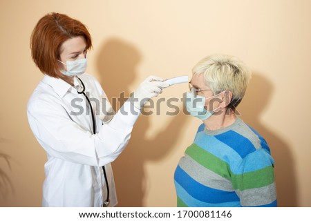 coronavirus pandemic. Quarantine. A doctor in a medical mask and gloves measures the temperature with a thermometer to an elderly patient in a medical mask and gloves.
