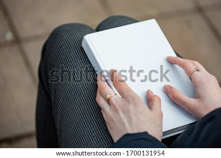 A girl holds a white book in her hands.