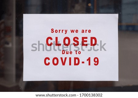 Closeup of information sign on the window of the store front : Sorry we are Closeddue to covid-19