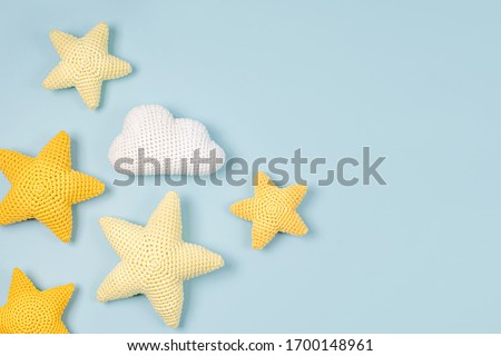 Knitted toy  yellow stars on blue 
 background. Baby stuff and accessories. Flat lay, top view