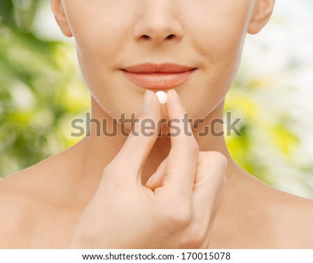 healthcare and medical concept - closeup picture of beautiful woman with pill