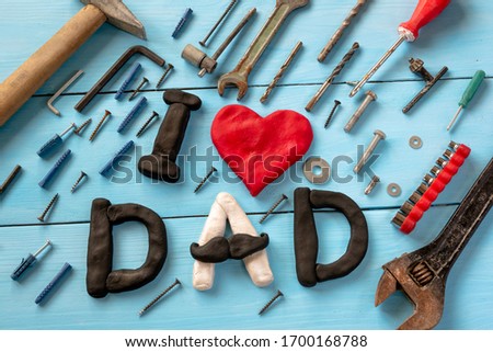 Funny inscription: "I love dad" in letters on a blue background with tools, a hammer, screws, a wrench, a screwdriver. 