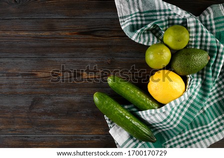 cucumber, avocado, lemon, lime, towel on a wooden background, fresh green and yellow vegetables and citrus, top view
