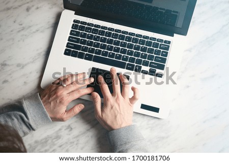 Mock-up of man hands using laptop on white marble surface.