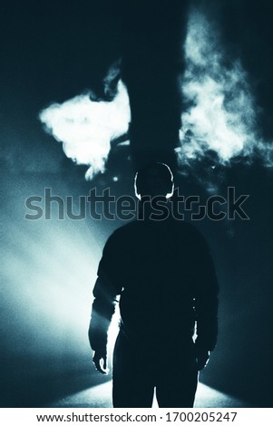 man standing alone silhouette the darkness, abstract mysterious sci fi fantasy concept, bright light rays from behind, person alone in dark background, human figure shadow in dark with fog and smoke