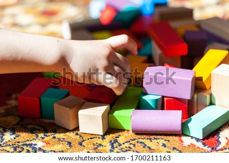 Playing colorful wooden cubes on carpet, hands
