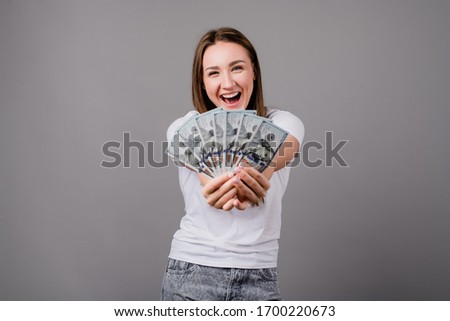 happy woman showing dollar bills money and smiling isolated on grey background
