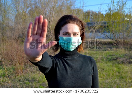 Stop Covid. A girl, woman in protective sterile medical mask on her face makes stopping hand gesture. Air pollution, virus, Chinese pandemic coronavirus concept. 
