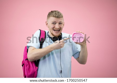 Frightened student holds an alarm clock in his hands and points a finger at it. Late for classes at the university. Irresponsible student. Forgot about the event. Overslept an interview concept