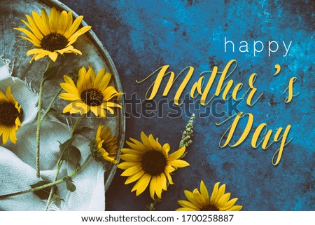 Yellow sunflower flat lay with blue vintage texture background, happy mothers day text on banner.