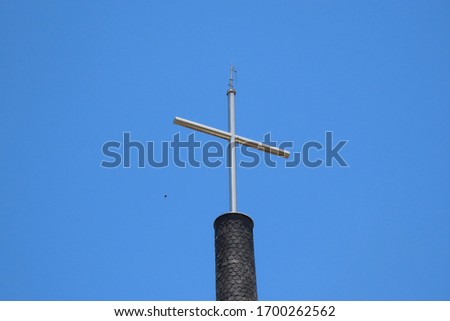 metal cross on top of a building with very blue sky in the background